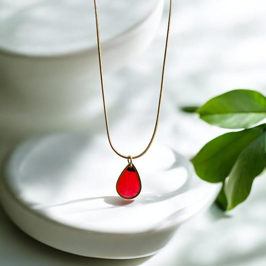 Drupt gouden ketting met minimalistische druppelvormige hanger waarin een echte rode klaproos is verwerkt.