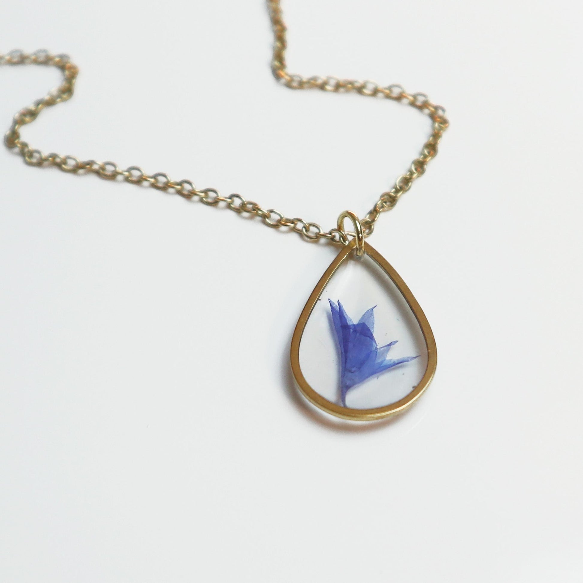 Drupt ketting met minimalistische gouden druppelhanger en een echte blauwe korenbloem in hars