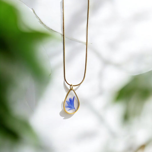 Drupt gouden ketting met druppelvormige hanger waarin een echte blauwe korenbloem is verwerkt.