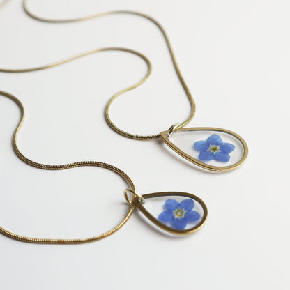 Drupt gouden ketting met druppelvormige hanger en een echt gedroogd blauw vergeet-mij-nietje bloemetje