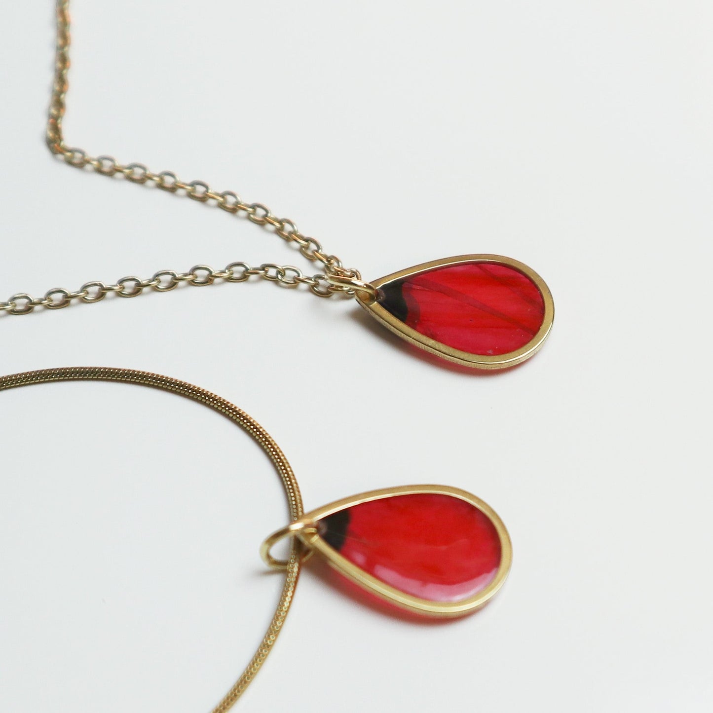Drupt gouden ketting met minimalistische druppelvormige hanger waarin een echte rode klaproos is verwerkt.
