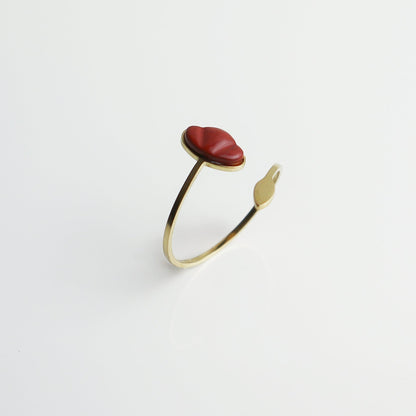 Drupt verstelbare ring van goud met een rode jaspis edelsteen in de vorm van een klaproos op een witte achtergrond.