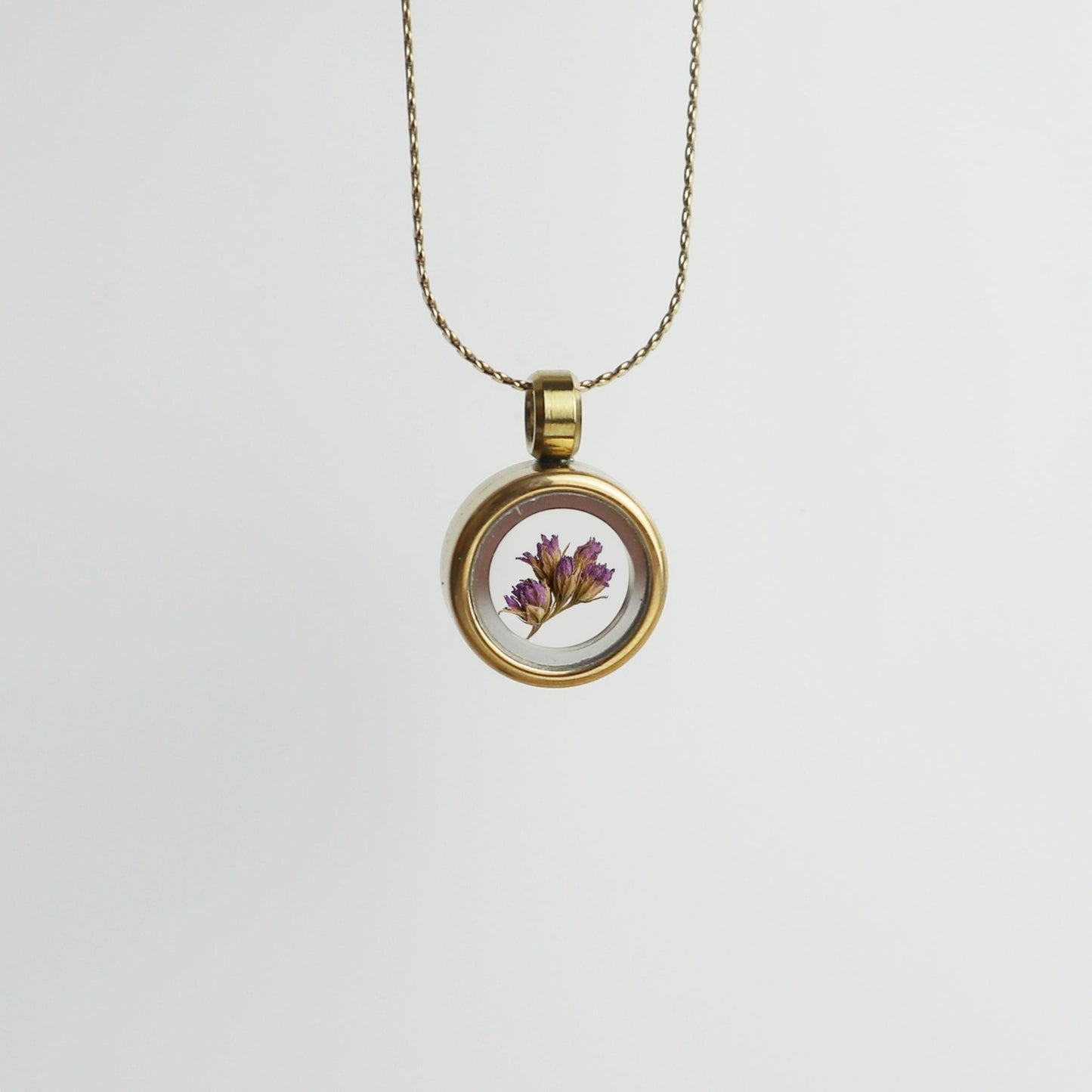 Drupt Koester hanger in goud met een gedroogd paars bloemetje in een glazen medaillon aan een fijne ketting