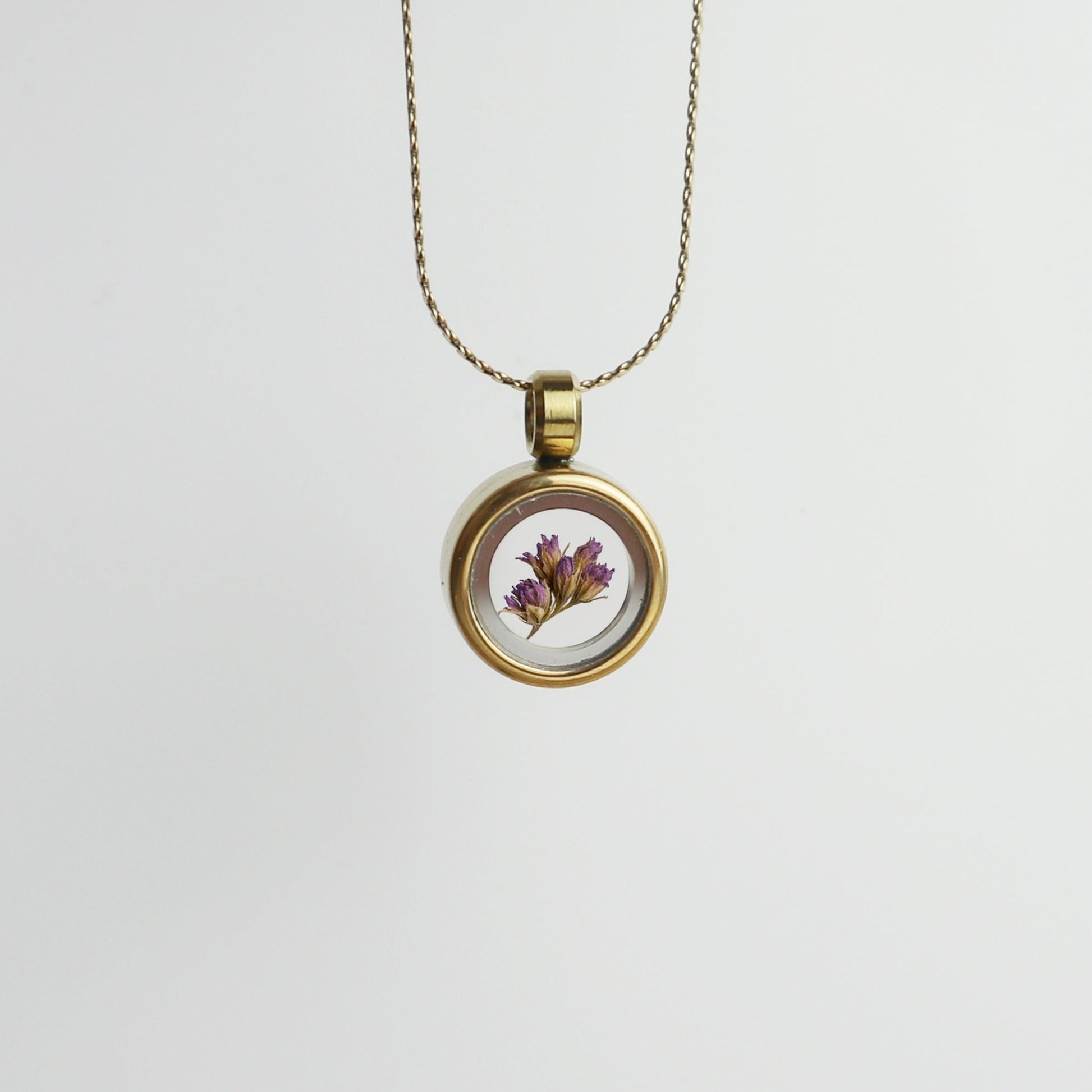 Drupt Koester hanger in goud met een gedroogd paars bloemetje in een glazen medaillon aan een fijne ketting