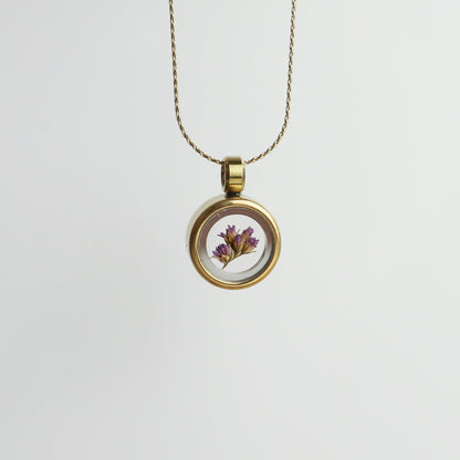 Drupt Koester hanger in goud met een gedroogd paars bloemetje in een glazen medaillon aan een fijne ketting