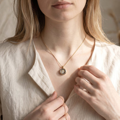 Drupt Koester hanger in goud gedragen aan een fijne ketting, perfect voor het bewaren van dierbare herinneringen.
