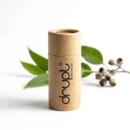 Drupt cadeauverpakking van bruin karton voor een Koester hanger, gepresenteerd met een takje eucalyptus.