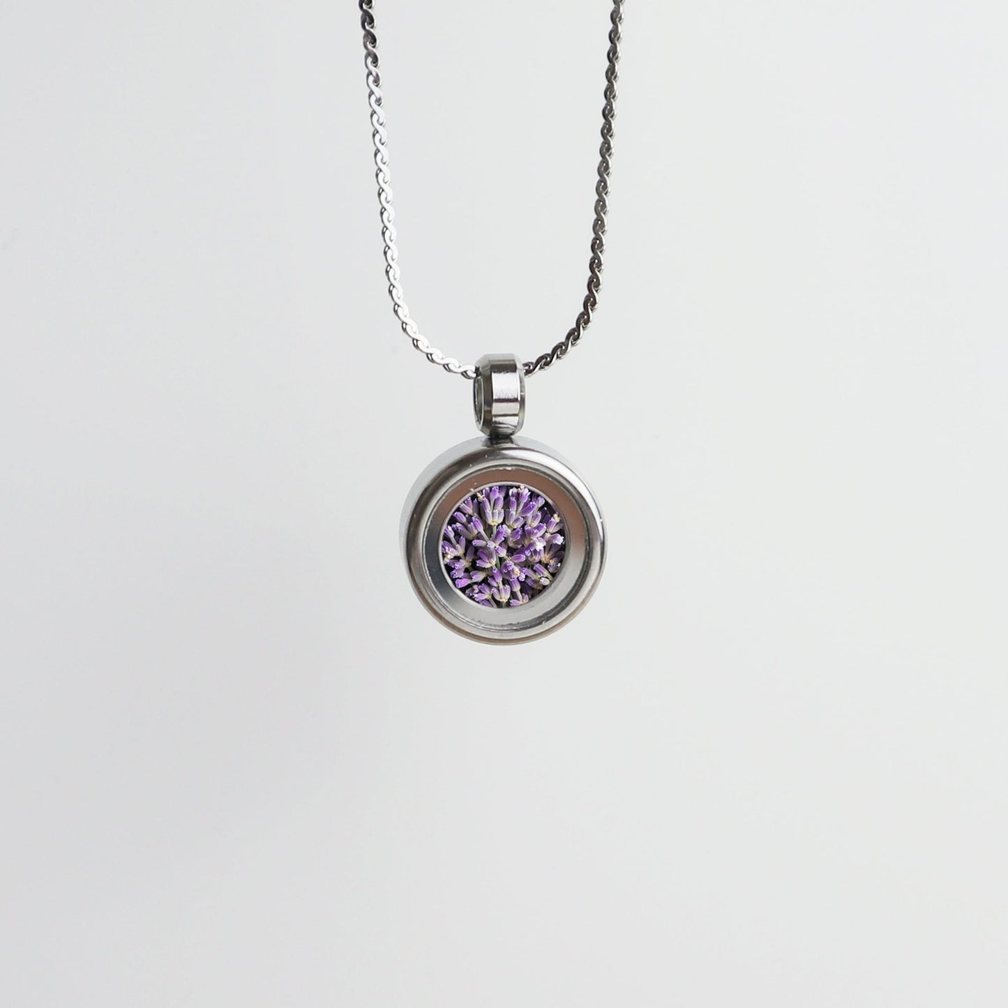 Drupt Koester zilveren hanger met paarse lavendelbloemetjes aan een fijne ketting tegen een witte achtergrond