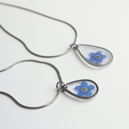 Drupt zilveren druppelvormige ketting met een echt gedroogd blauw vergeet-mij-nietje in een minimalistisch design.