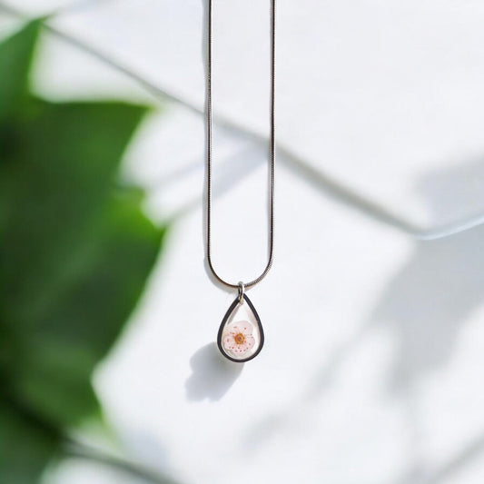 Drupt ketting met zilveren druppelvormige hanger en een delicate roze pruimenbloesem in hars.