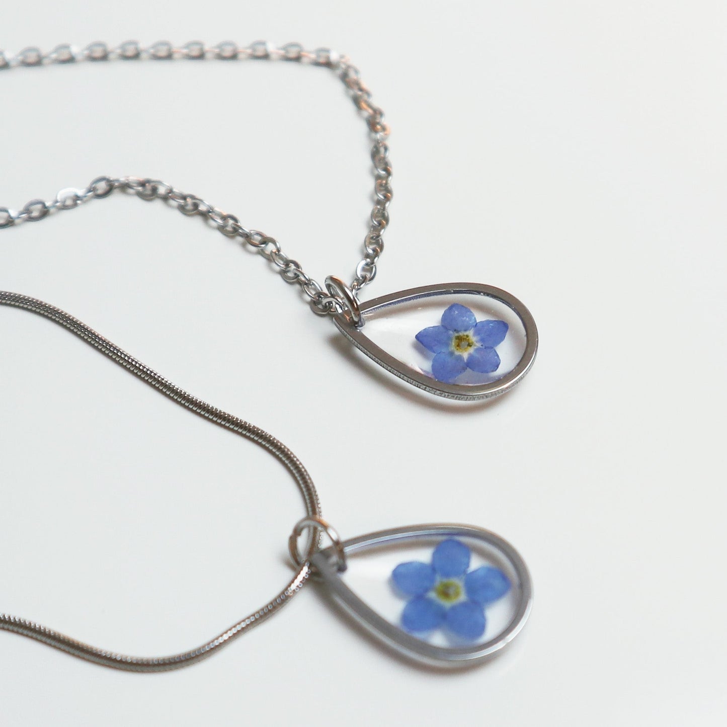 Drupt zilveren druppelvormige hanger met een echt blauw vergeet-mij-nietje aan een ketting
