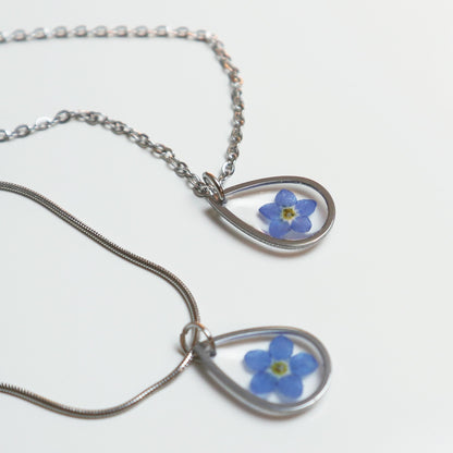 Drupt zilveren druppelvormige hanger met een echt blauw vergeet-mij-nietje aan een ketting