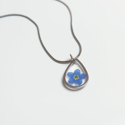 Drupt zilveren druppelvormige hanger met een echt blauw vergeet-mij-nietje aan een fijne ketting.