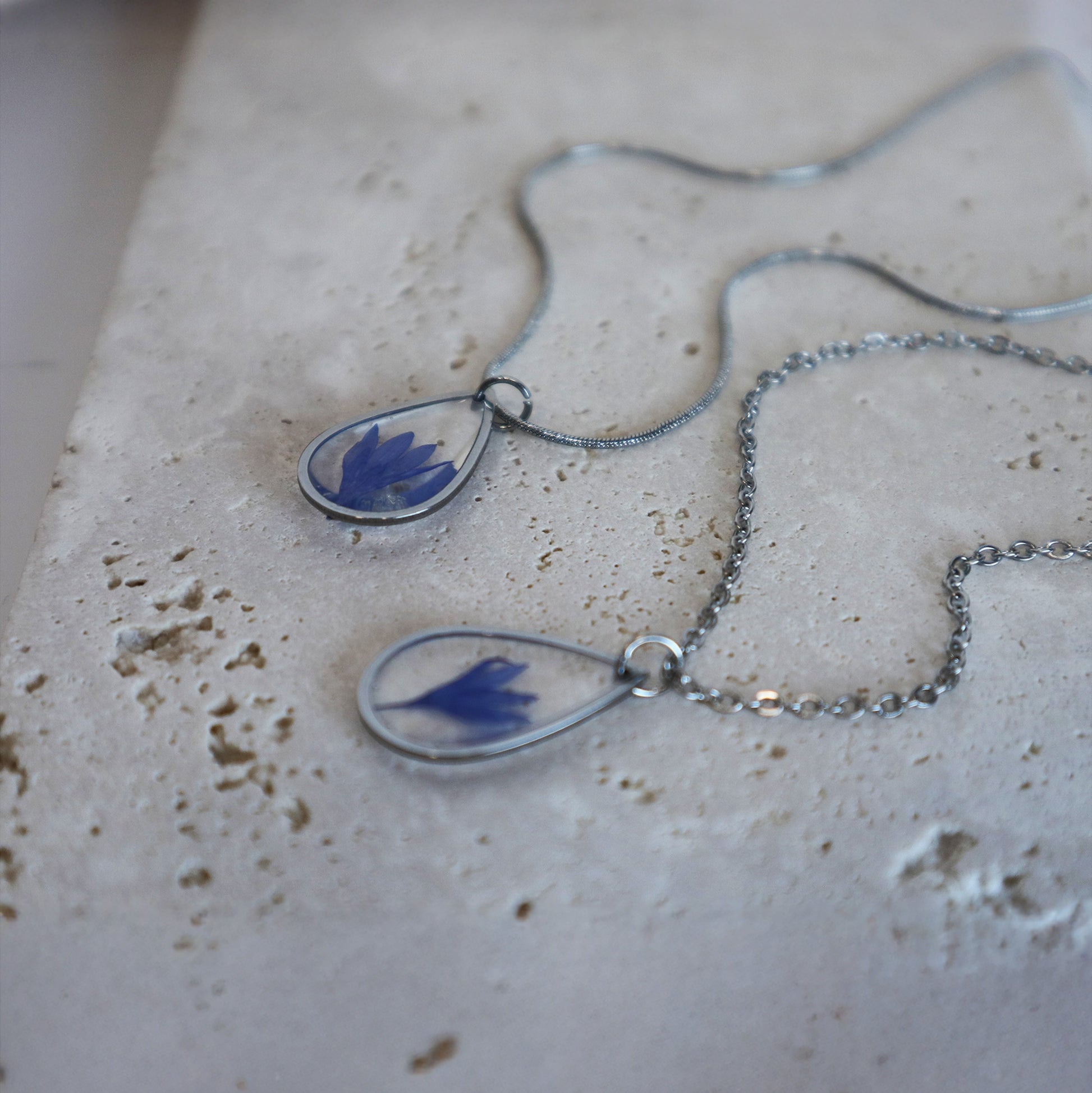 Drupt zilveren ketting met druppelvormige hanger en echte blauwe korenbloem, handgemaakt en minimalistisch design.