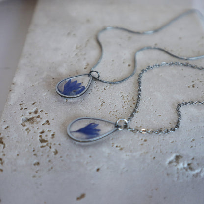 Drupt zilveren ketting met druppelvormige hanger en echte blauwe korenbloem, handgemaakt en minimalistisch design.