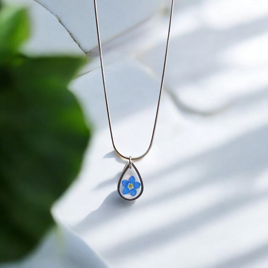 Drupt zilveren ketting met druppelvormige hanger en een echt blauw vergeet-mij-nietje bloemetje.