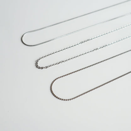 Drie verschillende zilverkleurige kettingen van Drupt op een witte achtergrond voor bij een hanger.