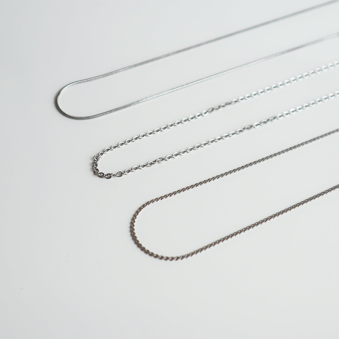 Drie verschillende zilverkleurige kettingen van Drupt voor de Koester hanger op een witte achtergrond.