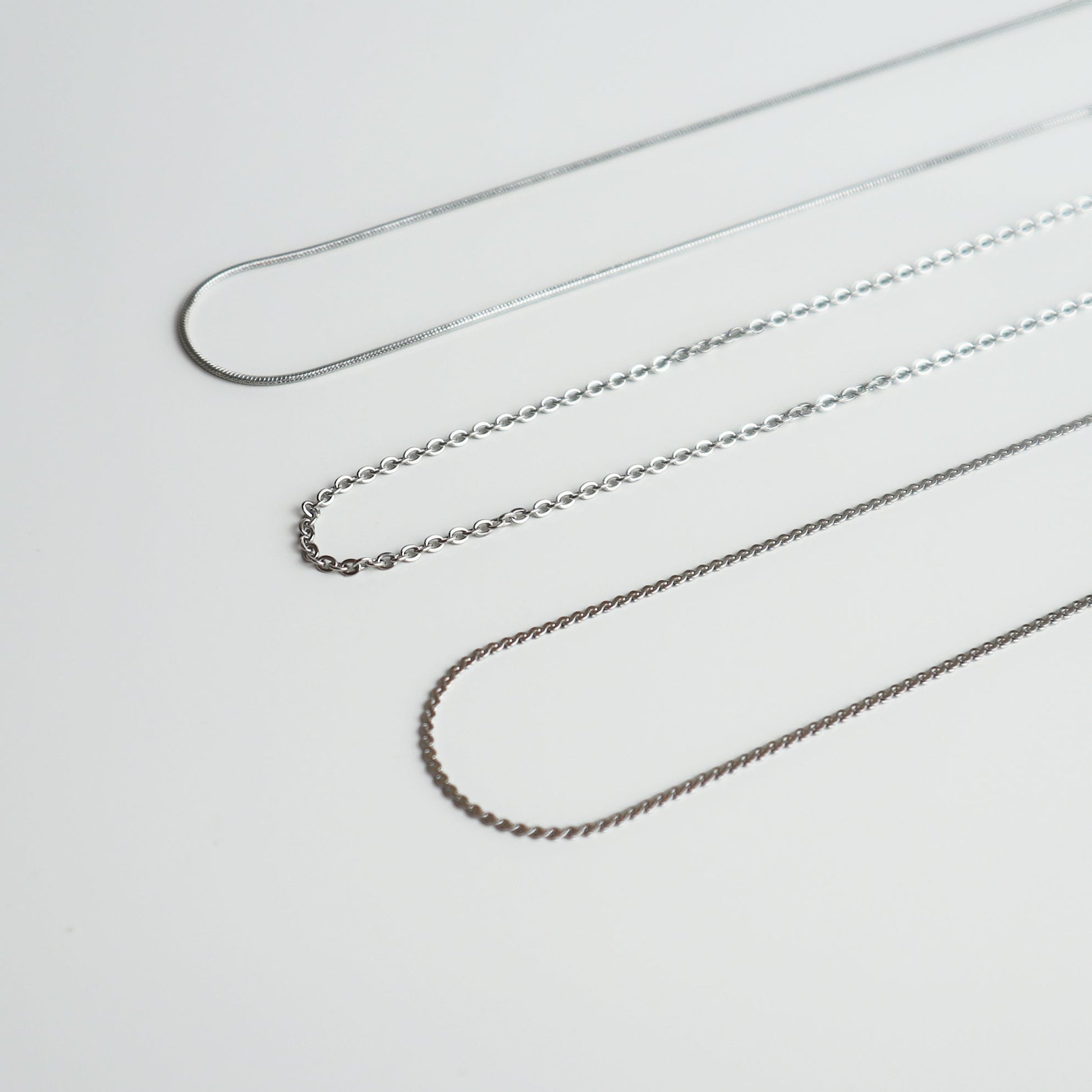 Drie verschillende zilverkleurige kettingen van Drupt voor de Koester hanger op een witte achtergrond.