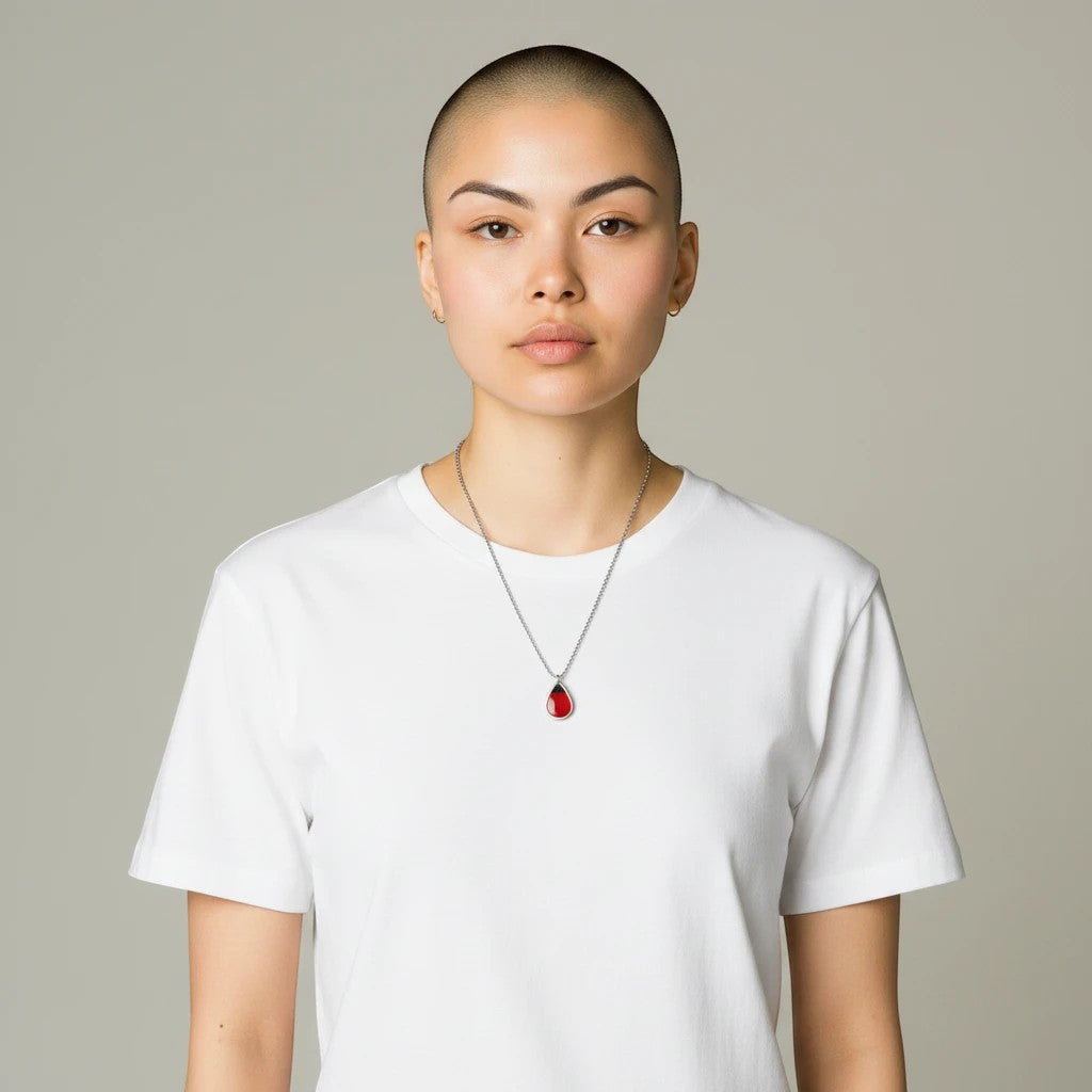 Drupt zilveren druppelvormige hanger met echte rode klaproos gedragen door een model in een wit T-shirt.