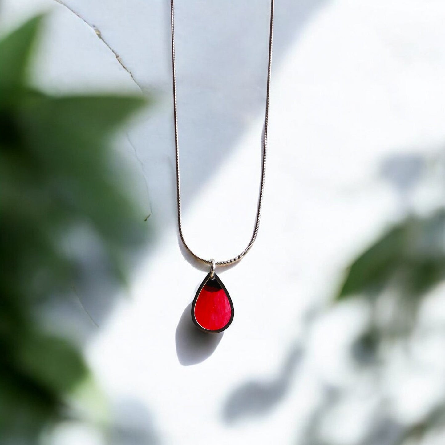 Drupt zilveren ketting met druppelvormige hanger waarin een rode klaproos is verwerkt voor een minimalistische look.