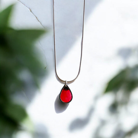 Drupt zilveren ketting met druppelvormige hanger waarin een rode klaproos is verwerkt voor een minimalistische look.