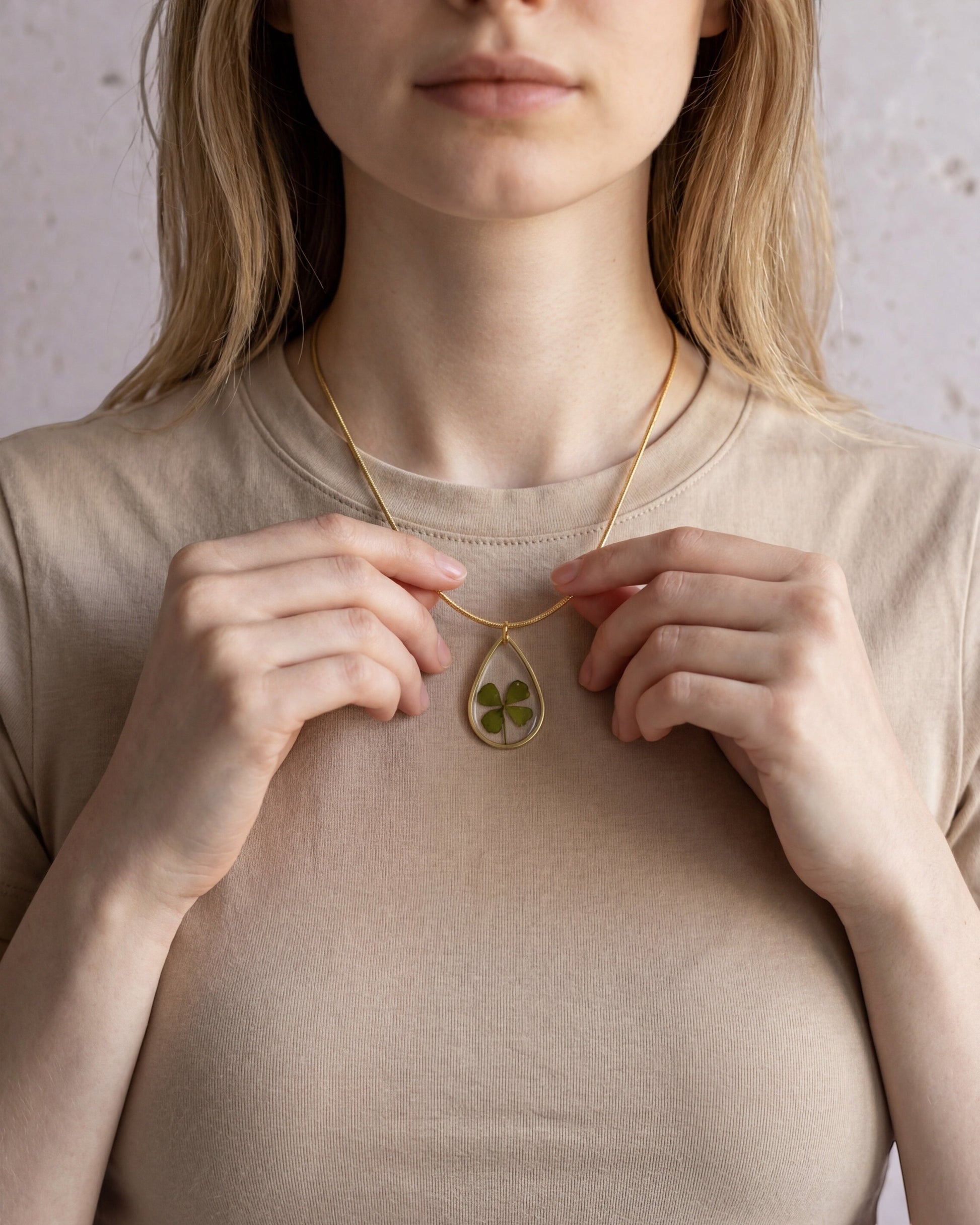 Drupt zilveren druppelvormige hanger met echt klavertjevier gedragen door een vrouw aan een subtiele ketting