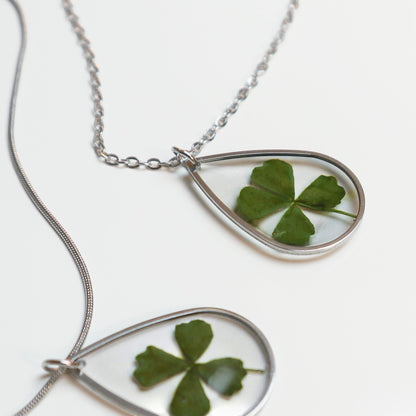 Drupt zilveren druppelvormige ketting met een echt klavertjevier in een minimalistisch handgemaakt sieraad