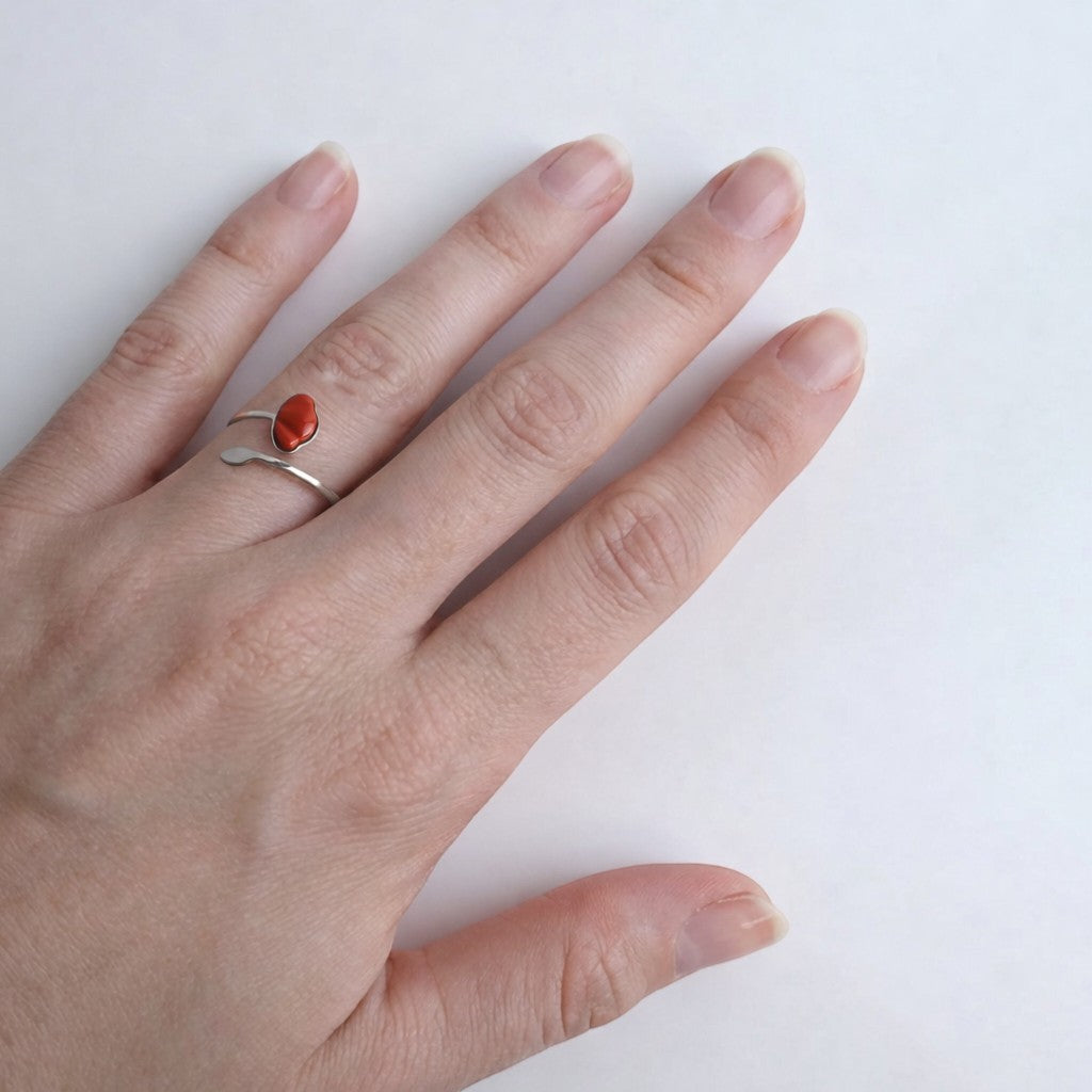 Drupt verstelbare zilveren ring met een rode jaspis edelsteen in de vorm van een klaproos om een vinger