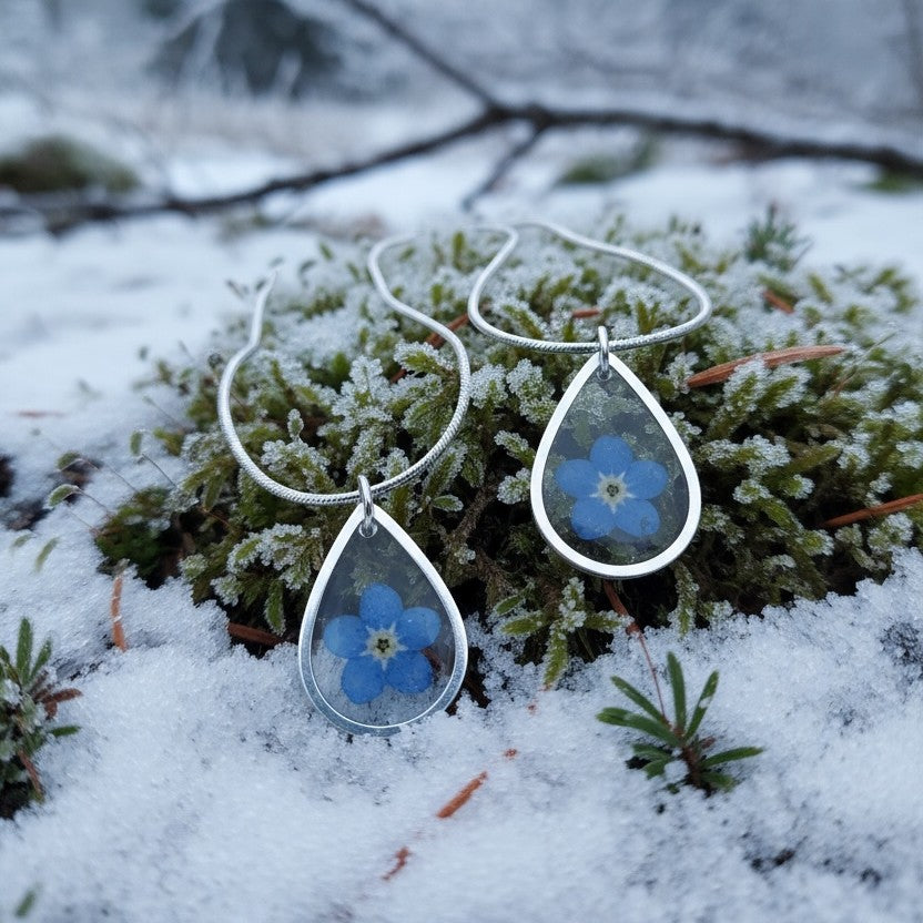 Drupt zilveren druppelvormige hanger met echt blauw vergeet-mij-nietje in de sneeuw